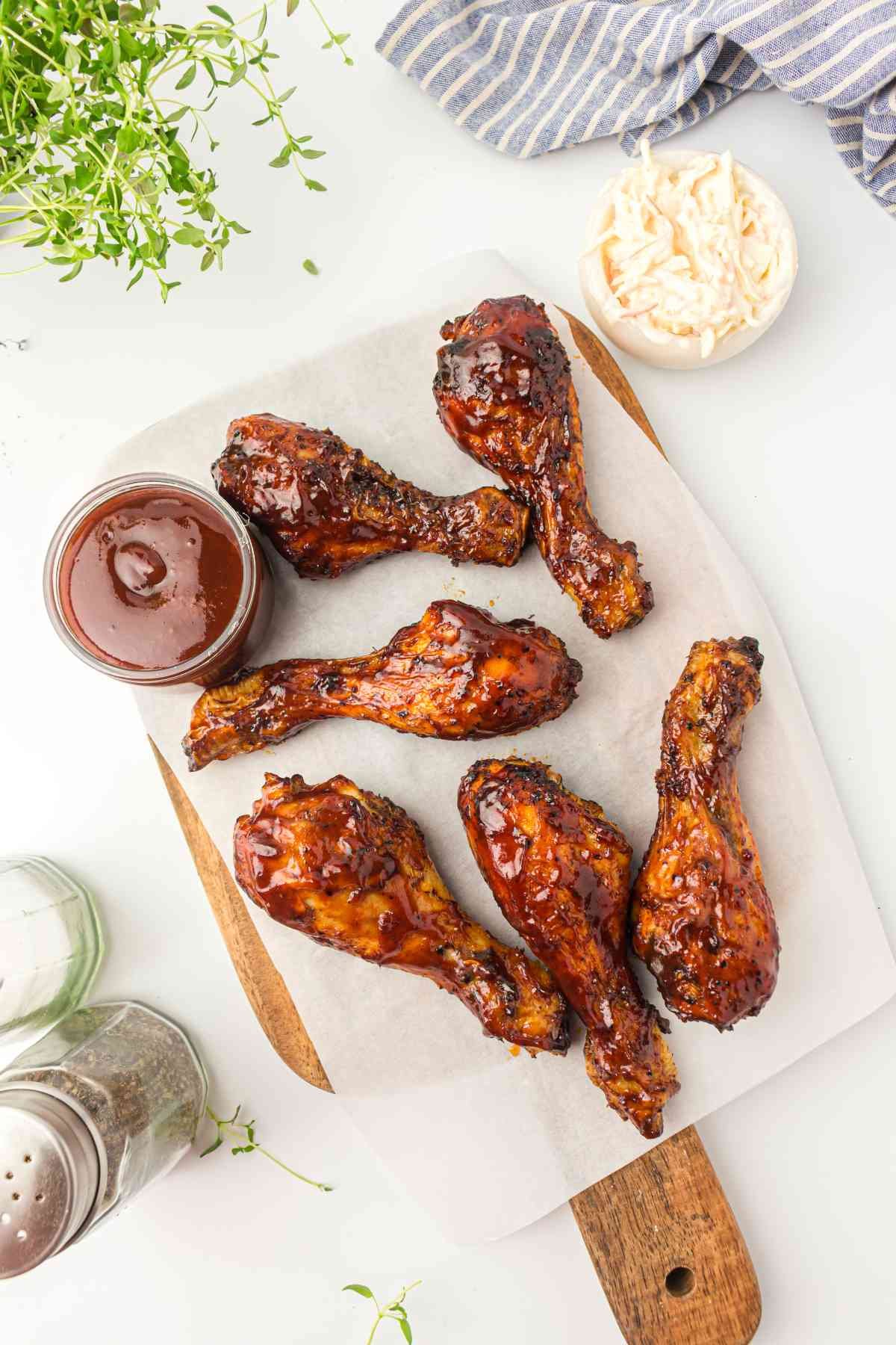 BBQ Chicken Drumsticks on a chopping board with BBQ sauce