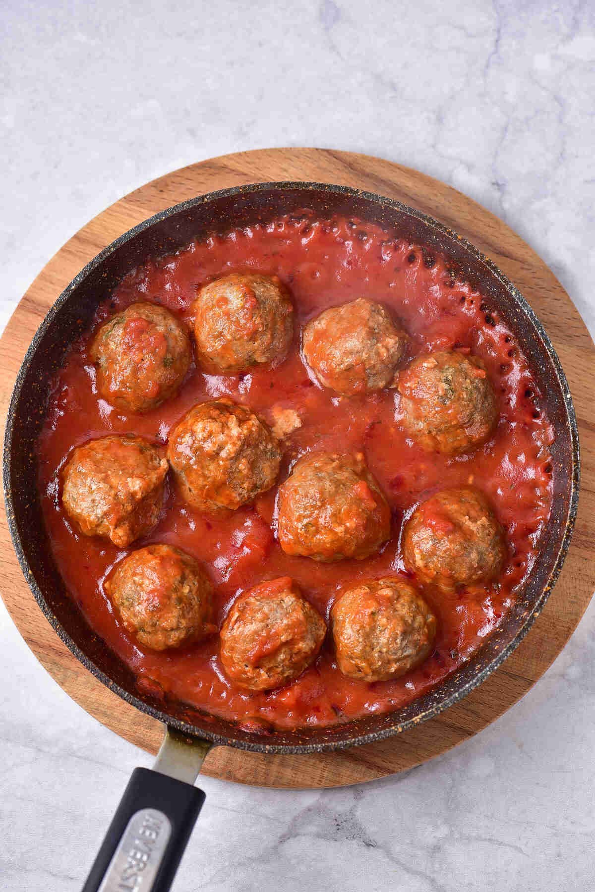 Baked Meatballs with Marinara Sauce in a black pan.