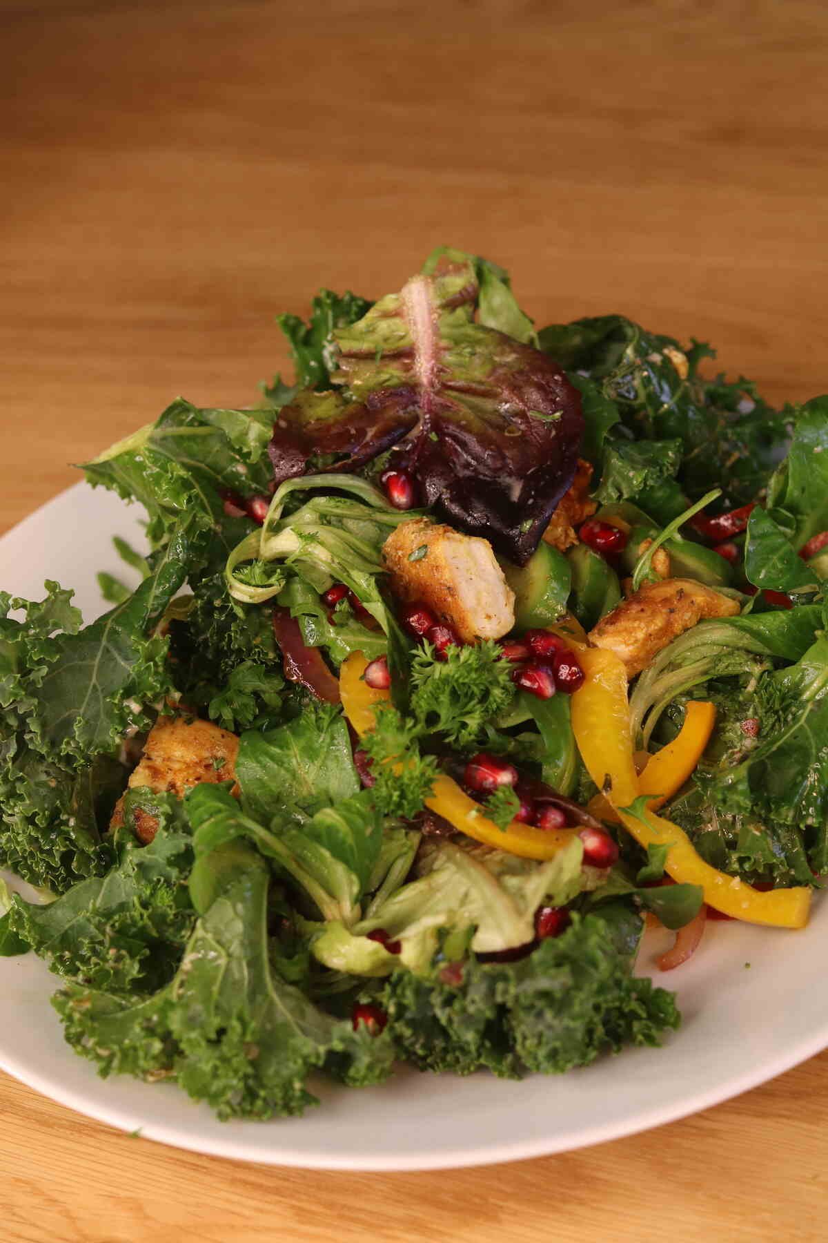 Kale Salad with Chicken topped with pomegranate seeds