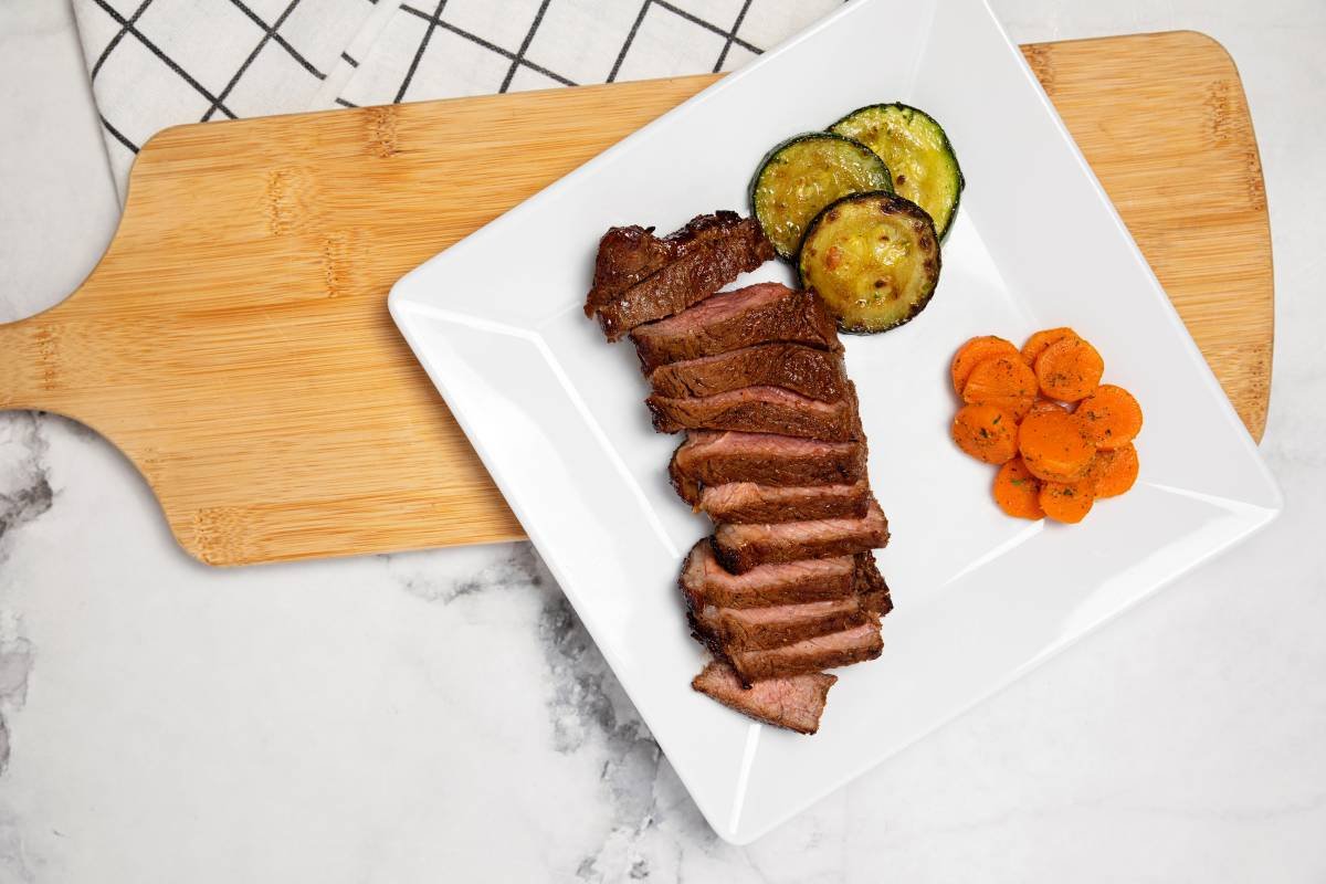 Slices of Sirloin Steak In A Platter with side vegetables.