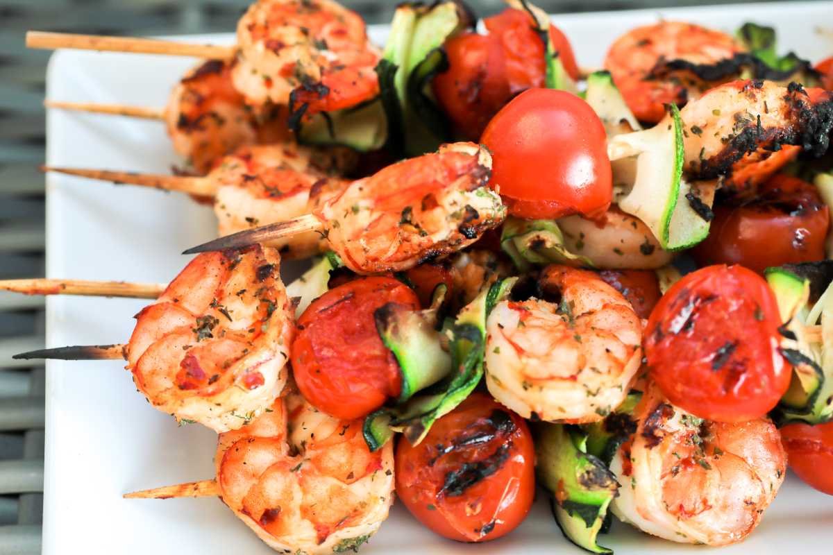 shrimp skewers are beautifully arranged on a white platter